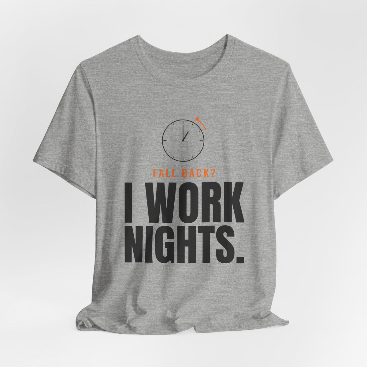 Heather gray night shift tee with a clock turning back and "FALL BACK? I WORK NIGHTS." in orange and bold type, on a soft gray backdrop