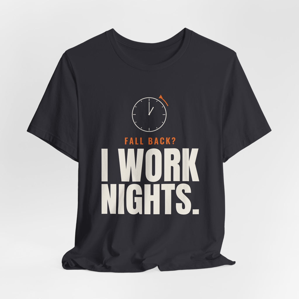 Charcoal night shift tee with a clock turning back and "FALL BACK? I WORK NIGHTS." in orange and bold type, on a soft gray backdrop
