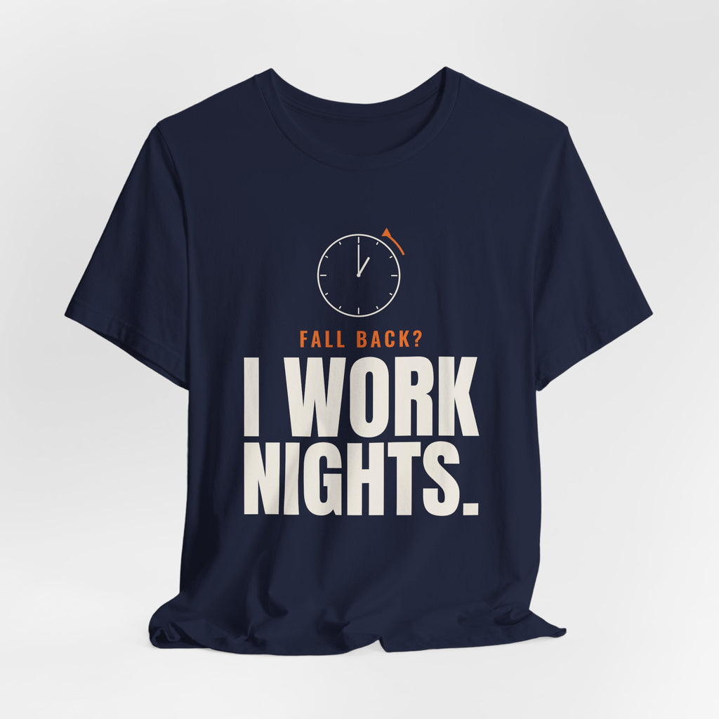 Navy night shift tee with a clock turning back and "FALL BACK? I WORK NIGHTS." in orange and bold type, on a soft gray backdrop
